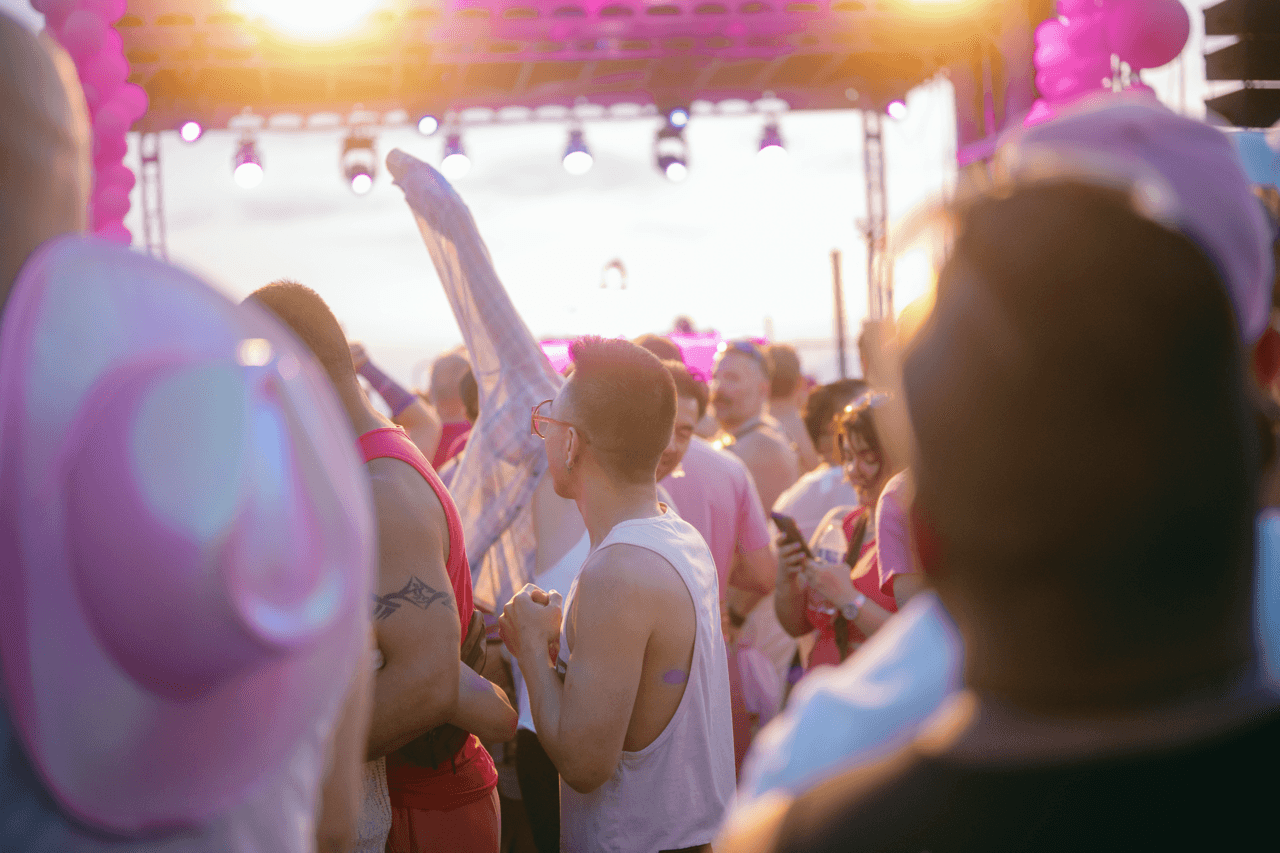 People dancing in a crowd full of people wearing pink at sunset.